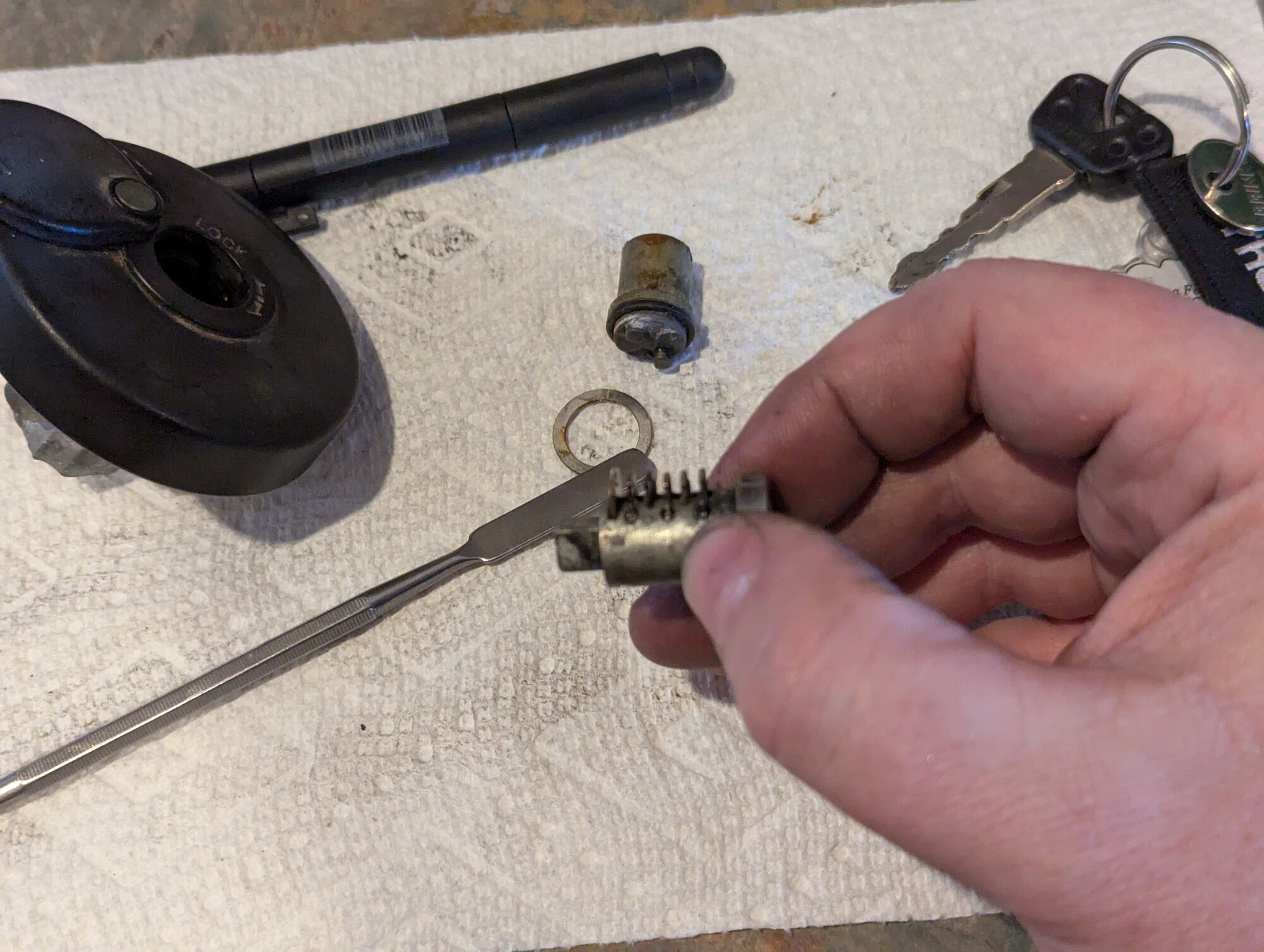 Once the pin is depressed, slide your tool to the 11:30 position to ensure the spring is fully compressed. Use a pen or thin rod to push on the center of the lock cylinder to extract it.