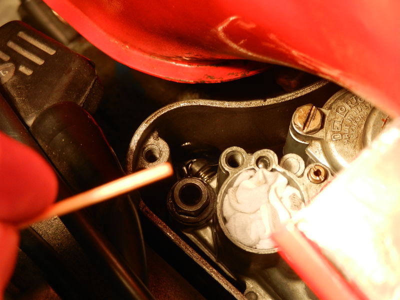 The end of the Q-tip pointing to the adjustment screw almost fully immersed in fuel at the back of the airbox