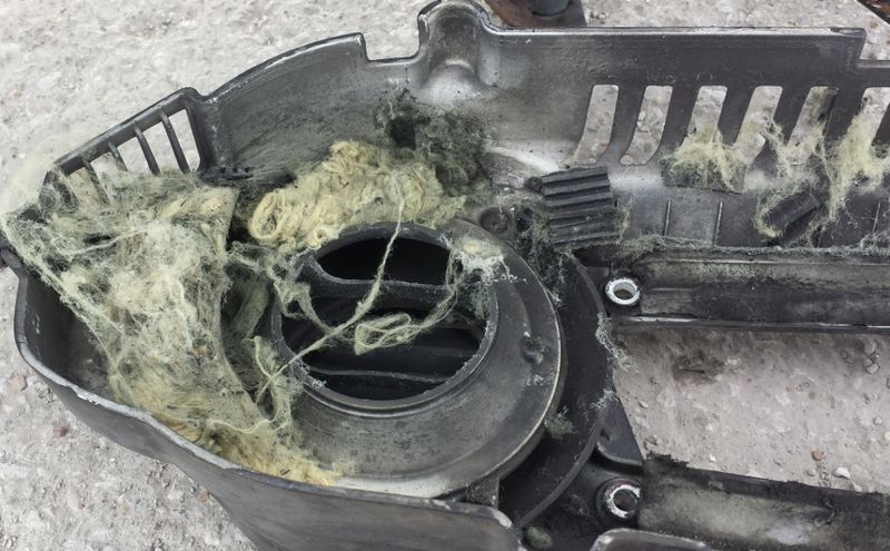 Inside the plastic cover.  See the outer belt rib chunks?