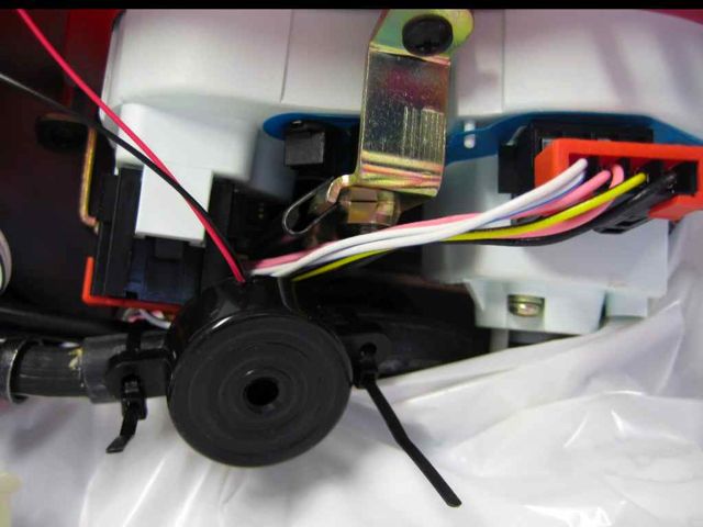 Using zip ties, I attached the piezo buzzer to a cable housing that ran right through the middle of the handle bar area, just underneath the instrument cluster.  I cleaned the ties up by clipping off the excess (after this photo was taken).