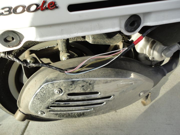 Cut off the insulating tape, between the black grommet and the 'ie' of the Vespa logo.