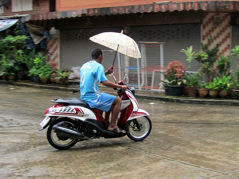 Modern Vespa riding in rain when it's really warm in city traffic