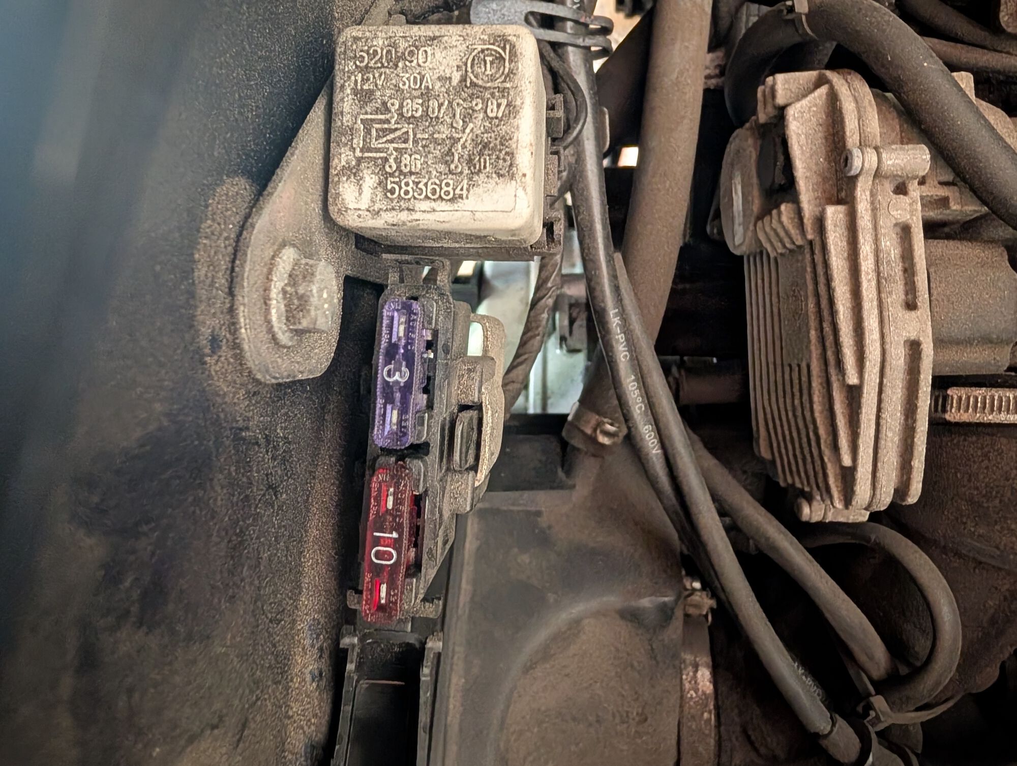 Under the seat, near the seat hinge