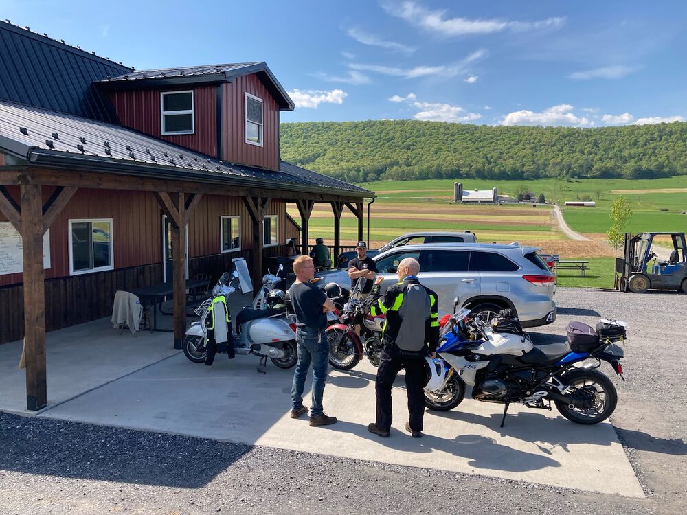 Two Vespa GTS scooters, a Triumph T100, and a BMW 1200RS gathered at the Nittany Valley Dairy near Jacksonville, Pennsylvania.